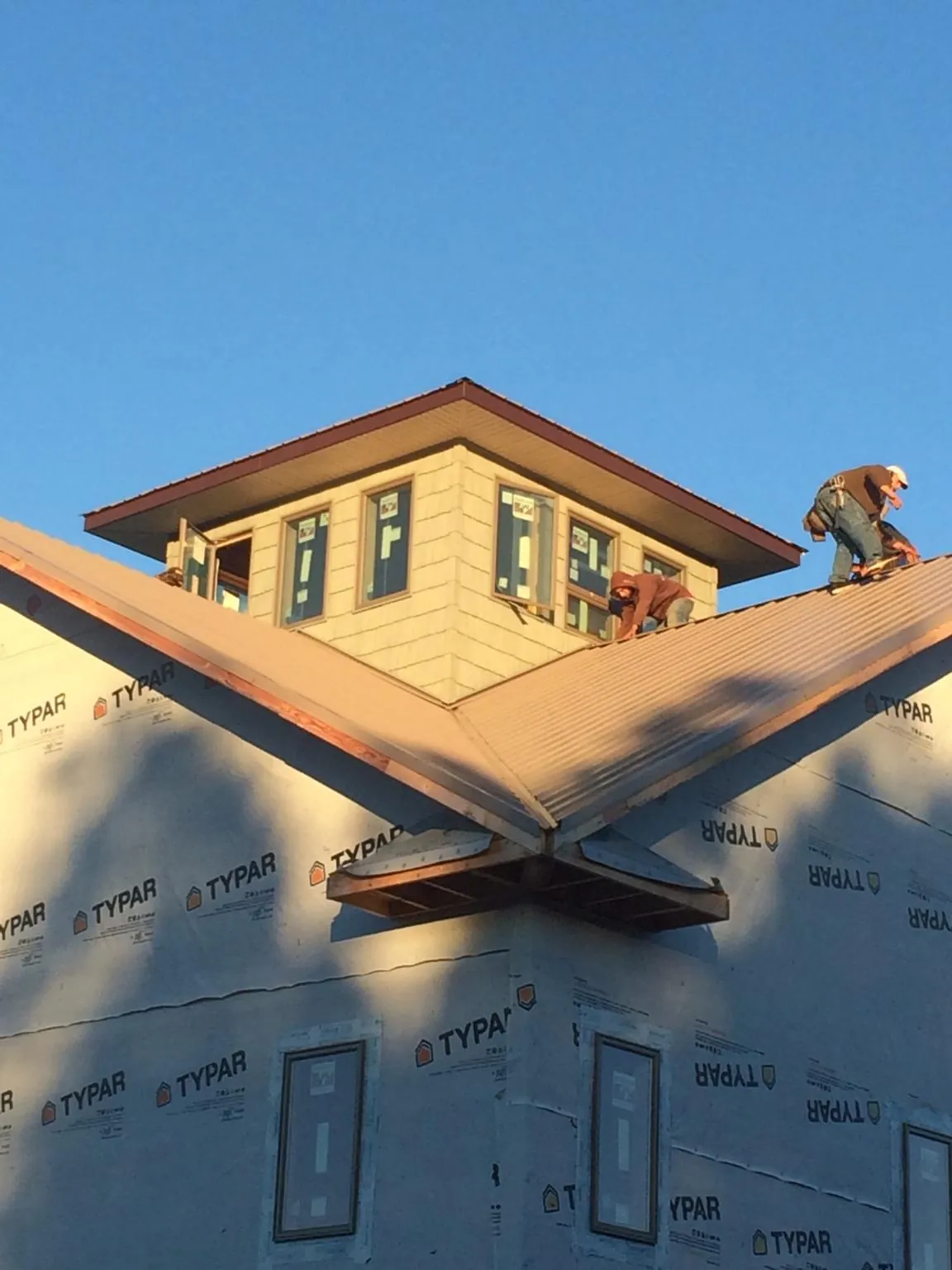 Roofers working around a rooftop cupola on a new metal roof at sunset — Roof Waterproofing in Avon Park by Roofing Brothers